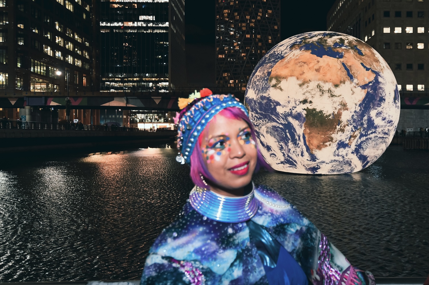 giant inflatable globe sitting on water in canary wharf light festival, london with me standing in front of it