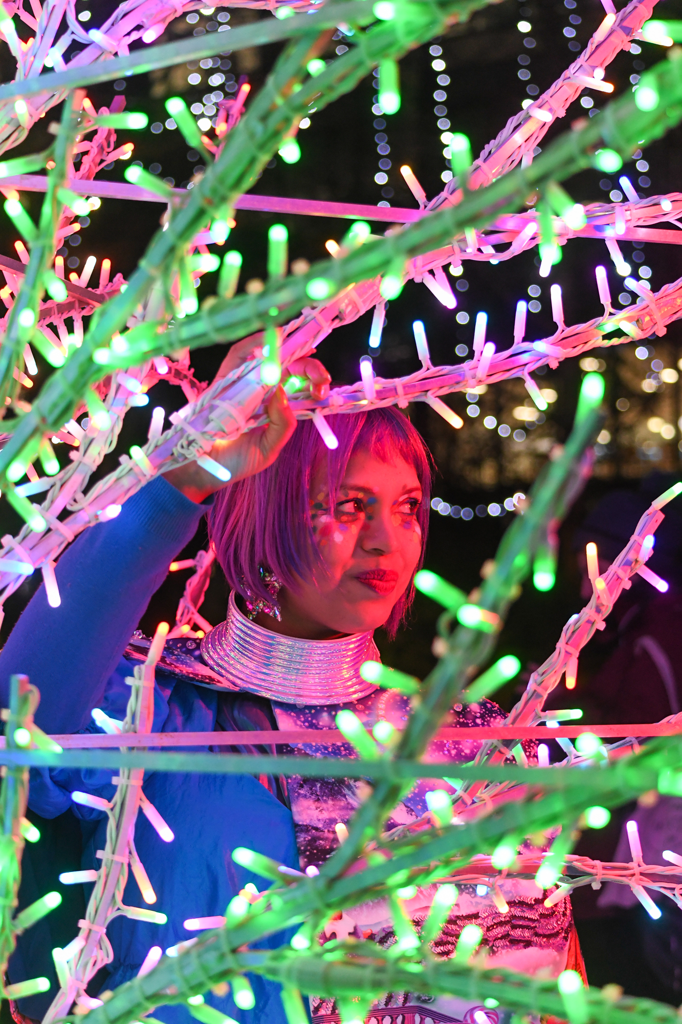 side angle pose behind fairy light trees