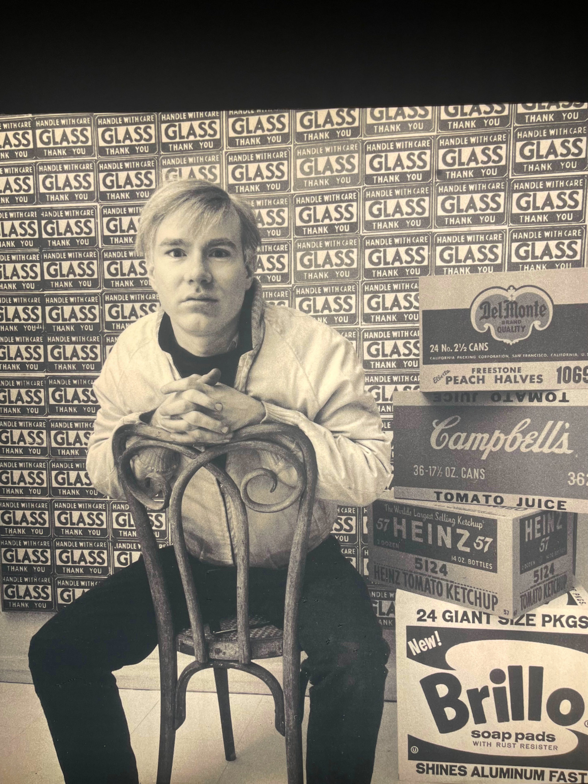 black and white photo of andy warhol sitting on a chair