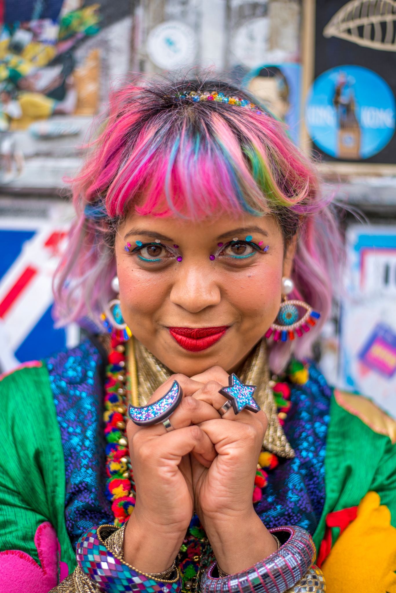 momtaz with her hands clasped under her chin with colourful clothes and accessories