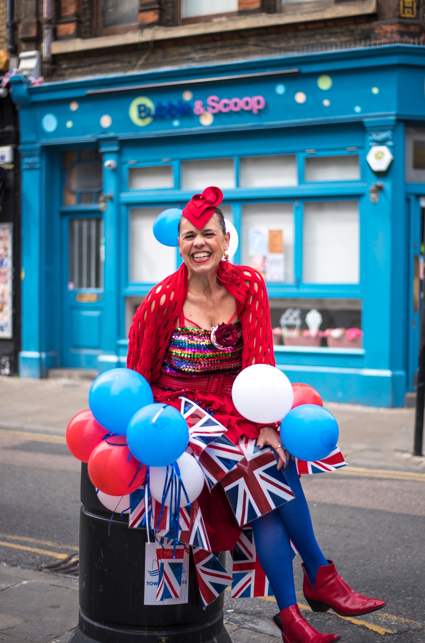 smiling happy lady wearing red white and blue sitting on top of a black street bin