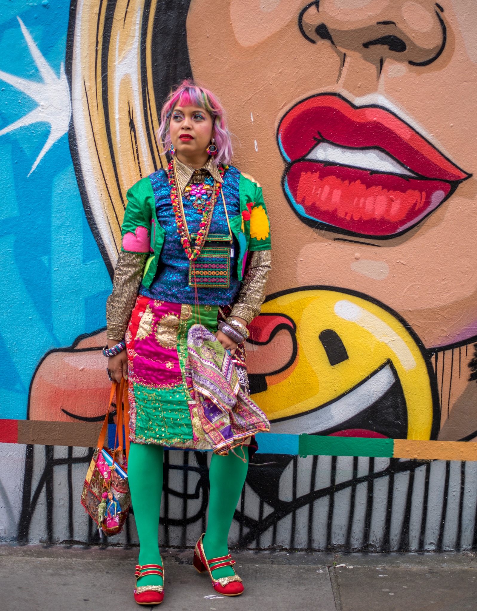 colourfully dressed girl with red lips standing against red lips in street art 