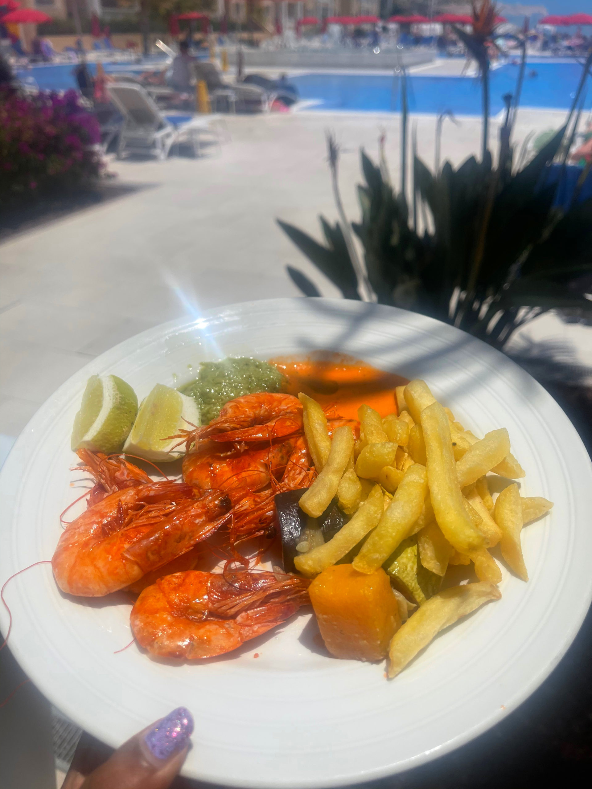 A plate of large  prawns with shells on with chips, dips and lemon wedges