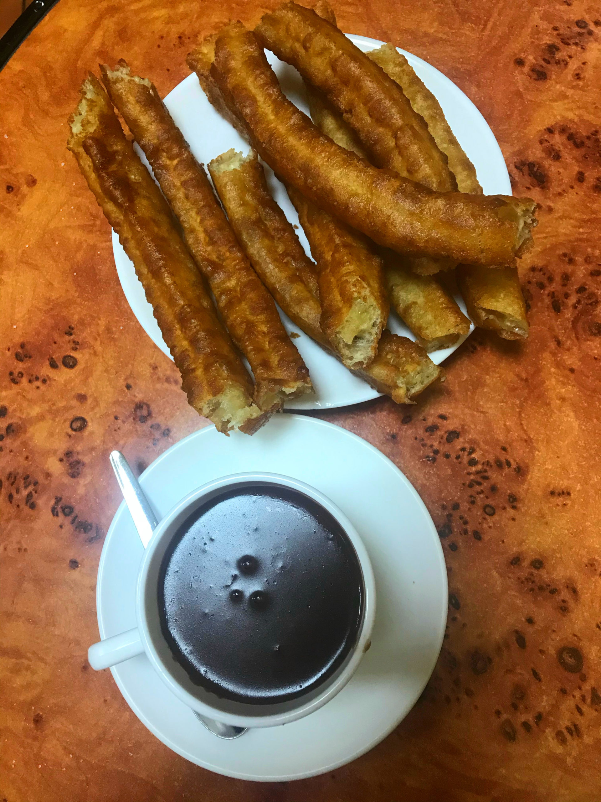 cup of hot chocolate and plate of churros shot from above