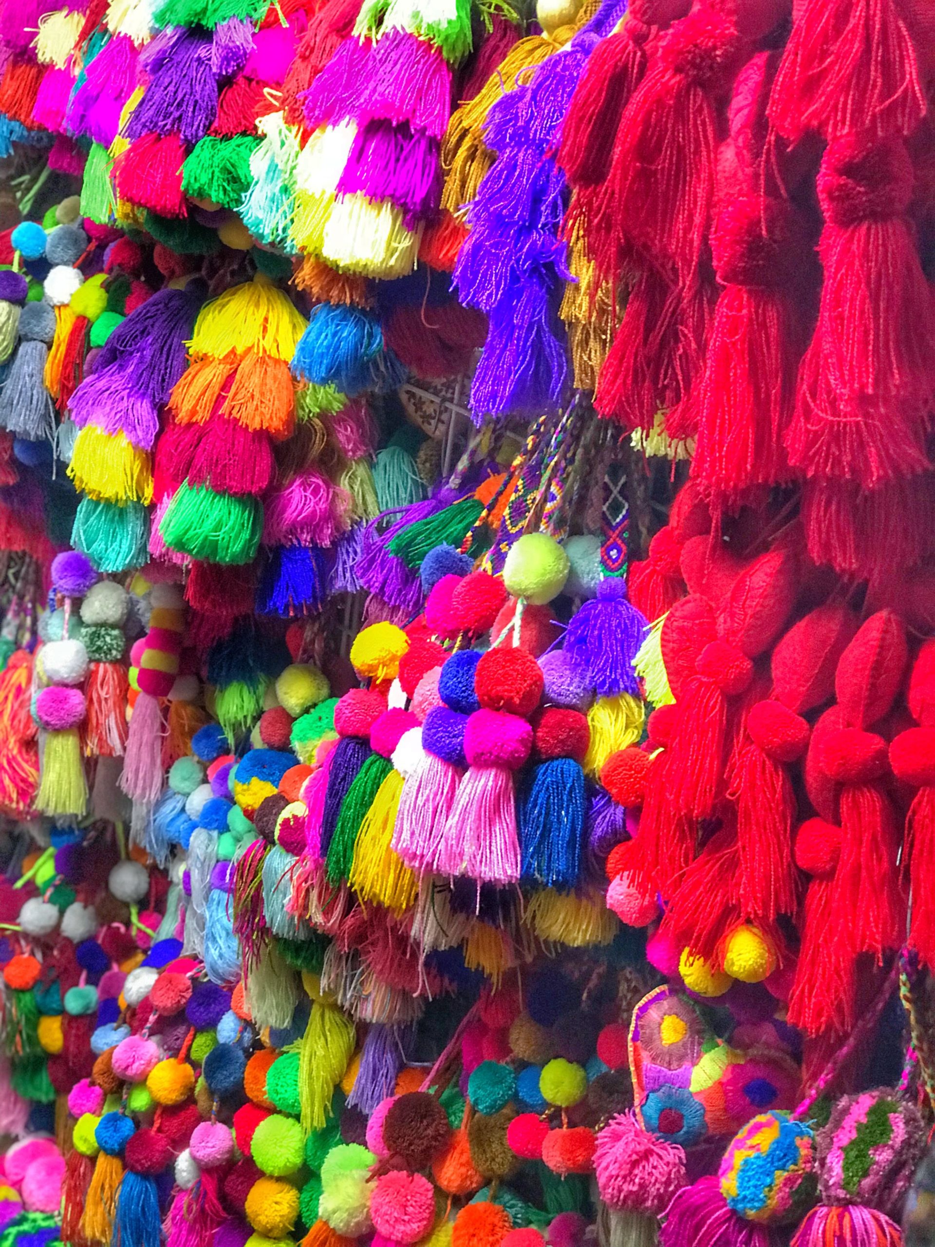 colourful pompoms and tassels hanging on a market stall in mexico