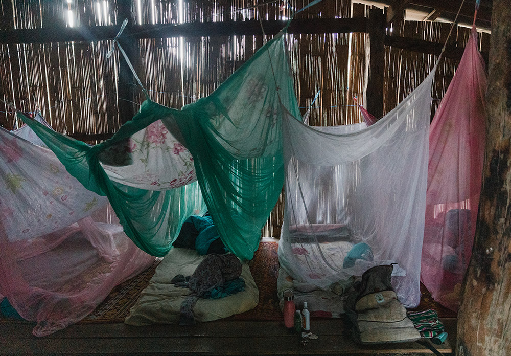 4 mosquito nets hanging above a large shared bed