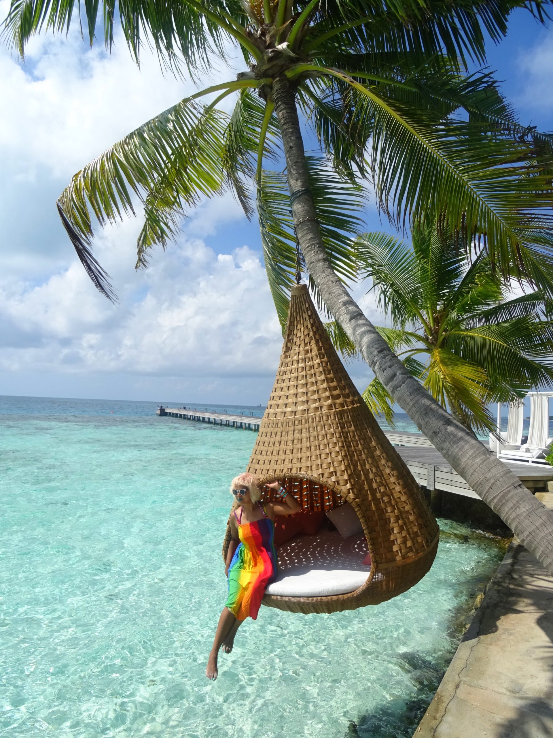 momtaz wearing a rainbow dress hanging in a basket chair over the indian ocean