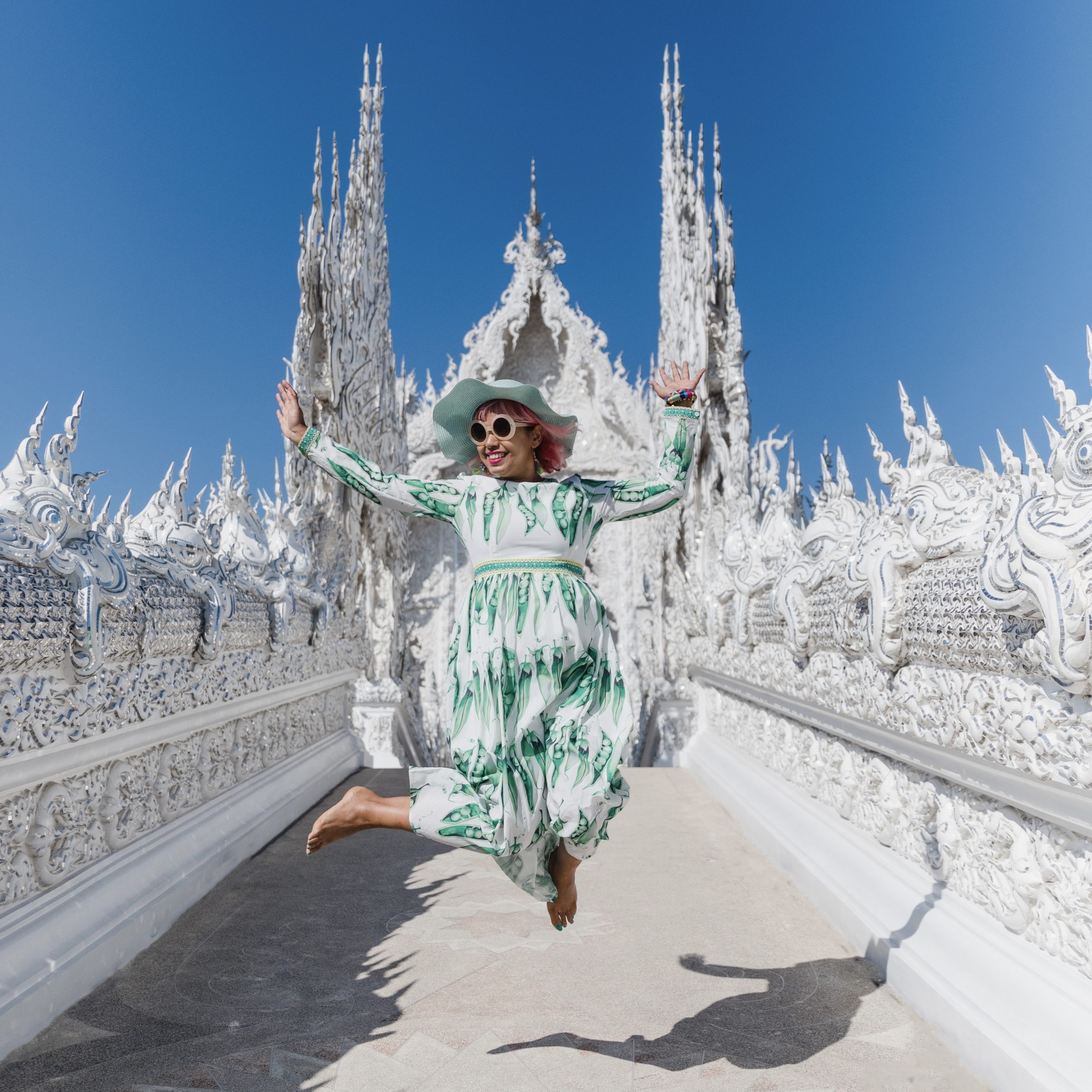 Momtaz leaping in the air in front of the white temple in Thailand