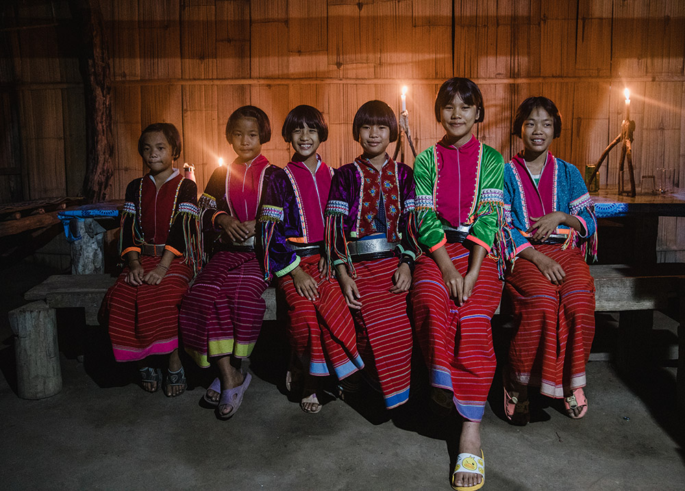 6 young girls sitting on a bench in traditional dress smiling