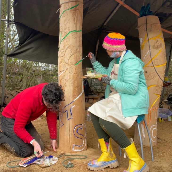 tow people painting large wooden totems
