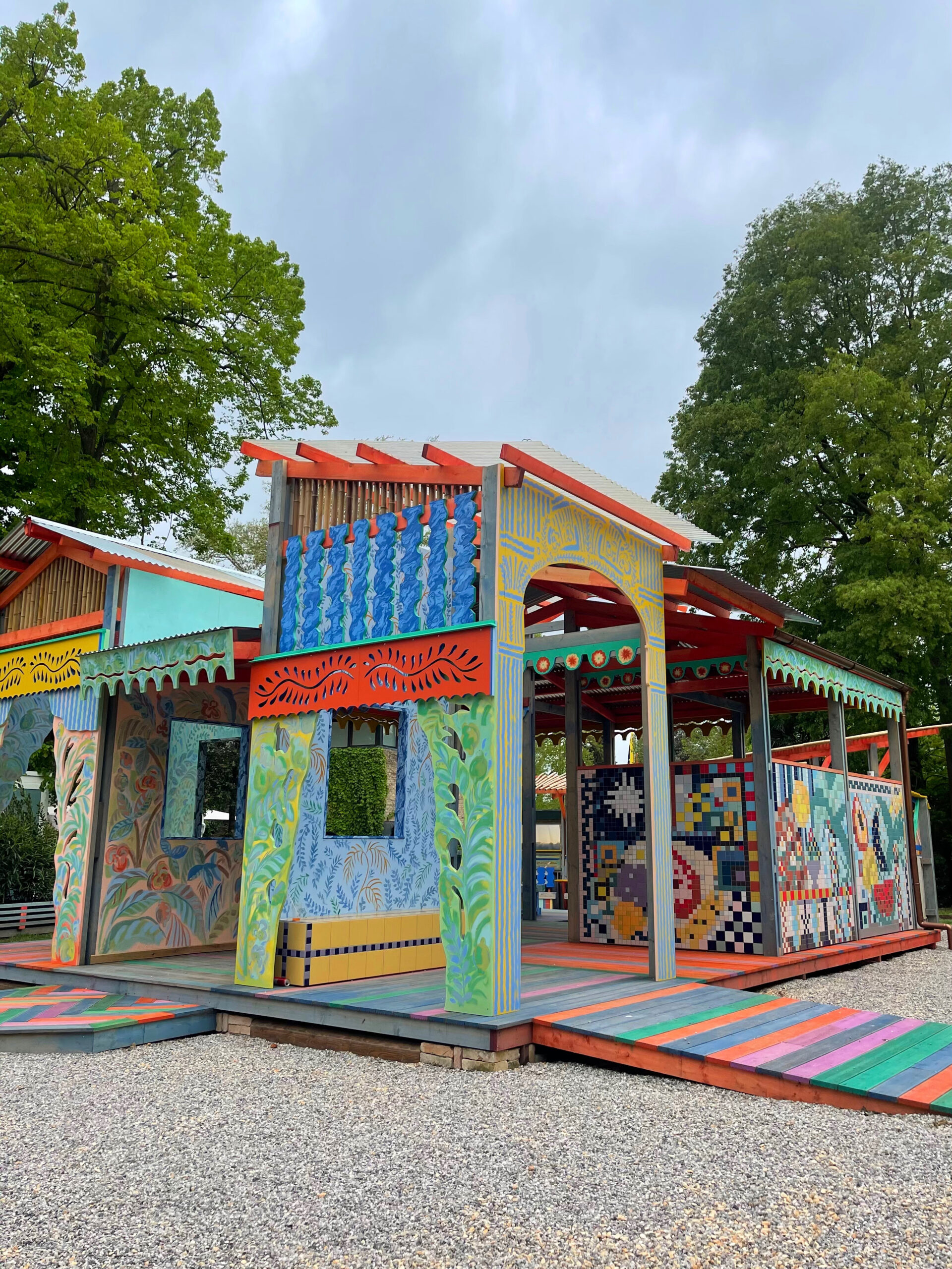 a large colourful outdoor pavilion with seating areas, painted and mosaic