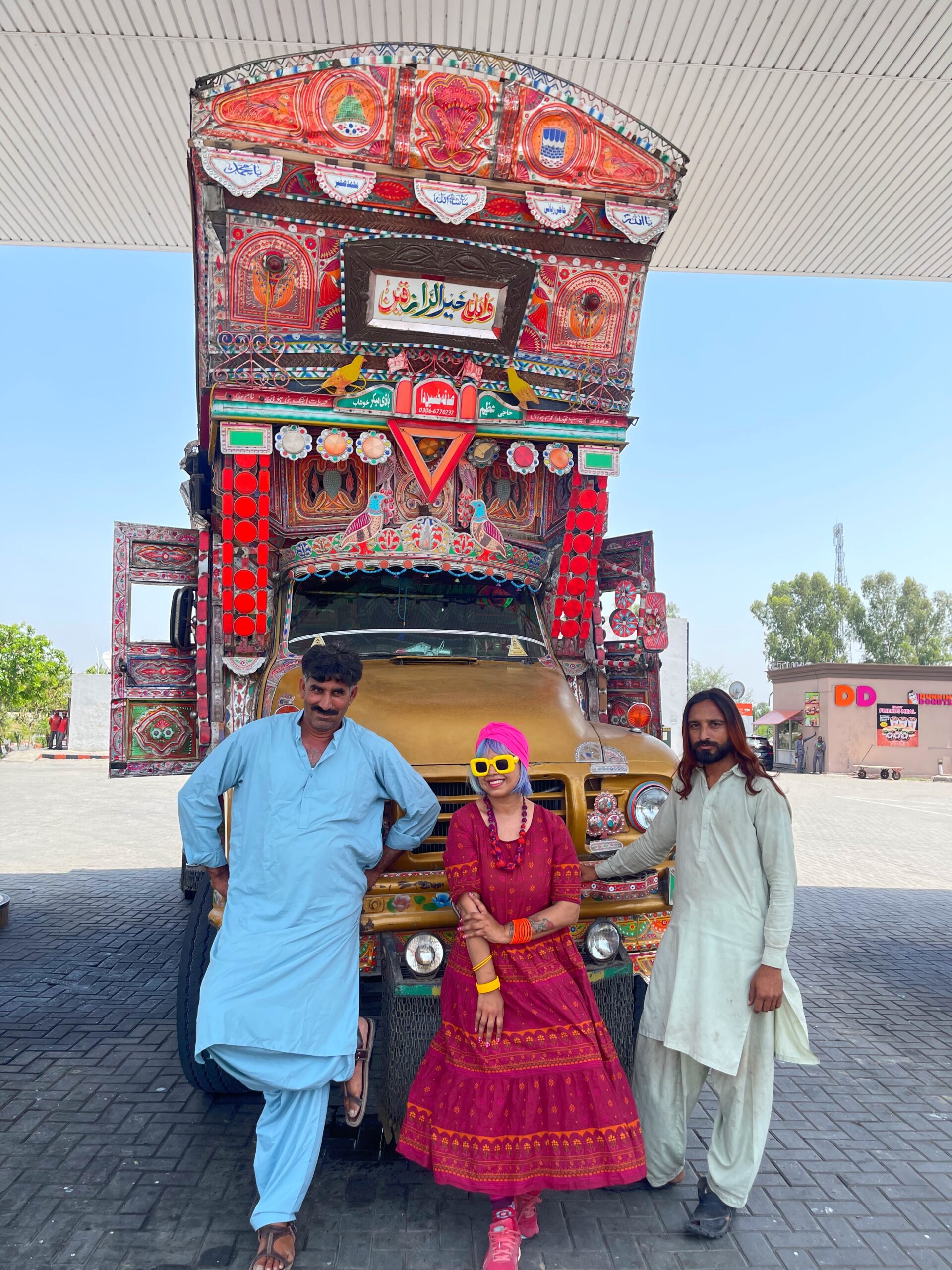 a traditional pakistan truck, driver and assistant beside it