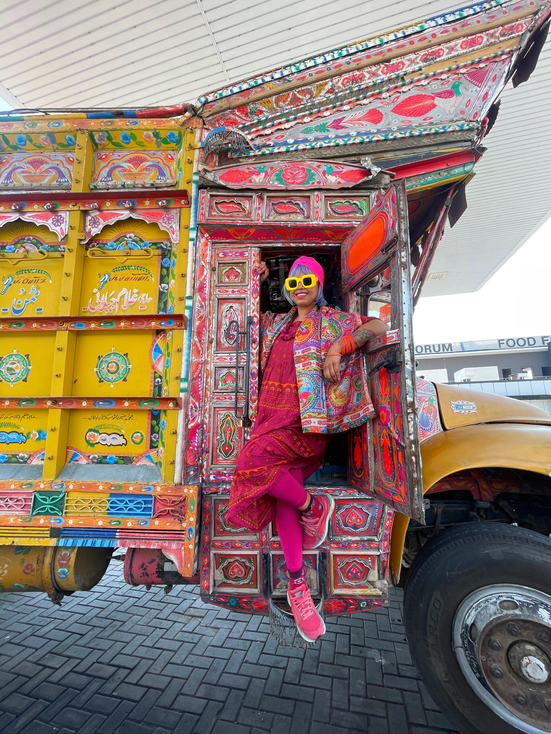 momtaz sitting and hanging out of a colourful pakistani truck art