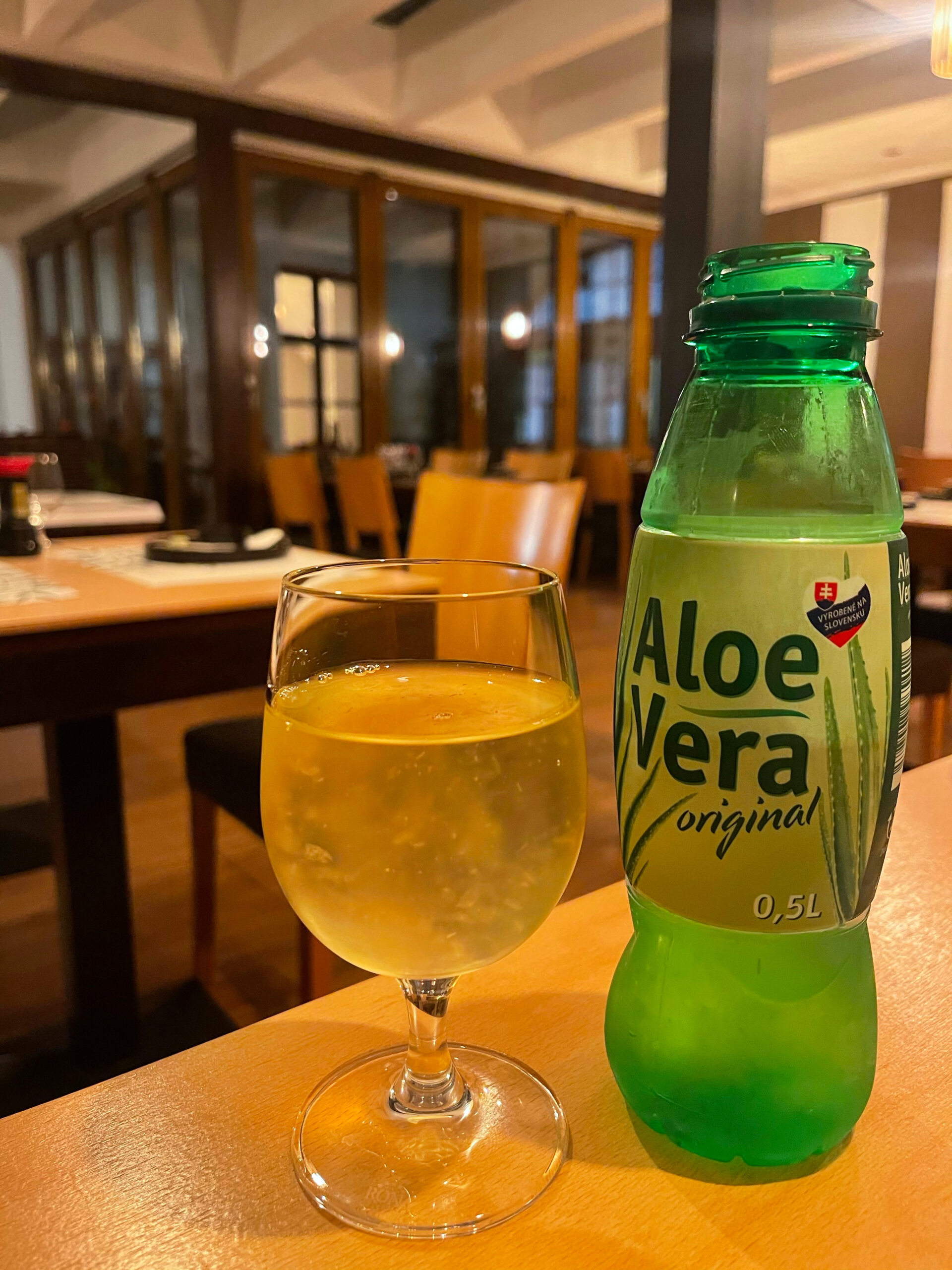 a green bottle that says aloe vera original with the contents poured in the glass looking refreshing