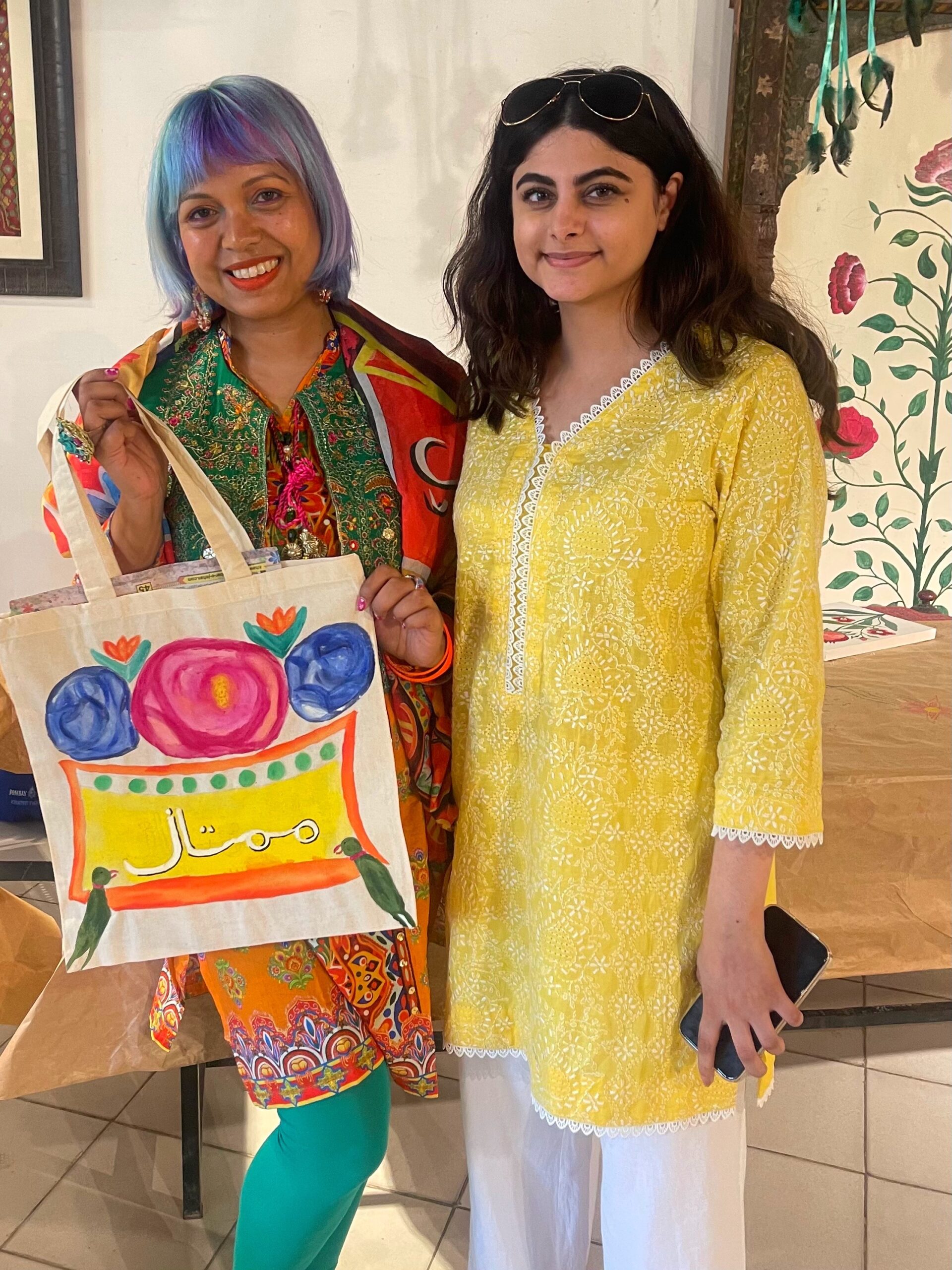 Momtaz holding up the tote bag she painted with her name in urdu