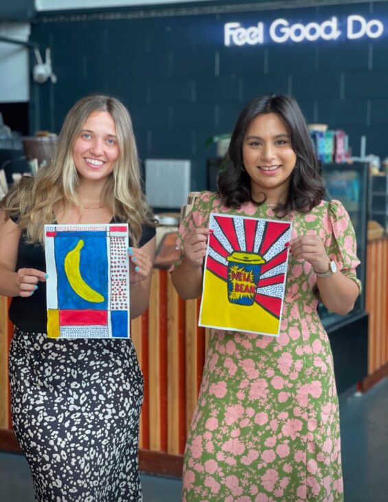 two girls holding up pop art inspired paintings