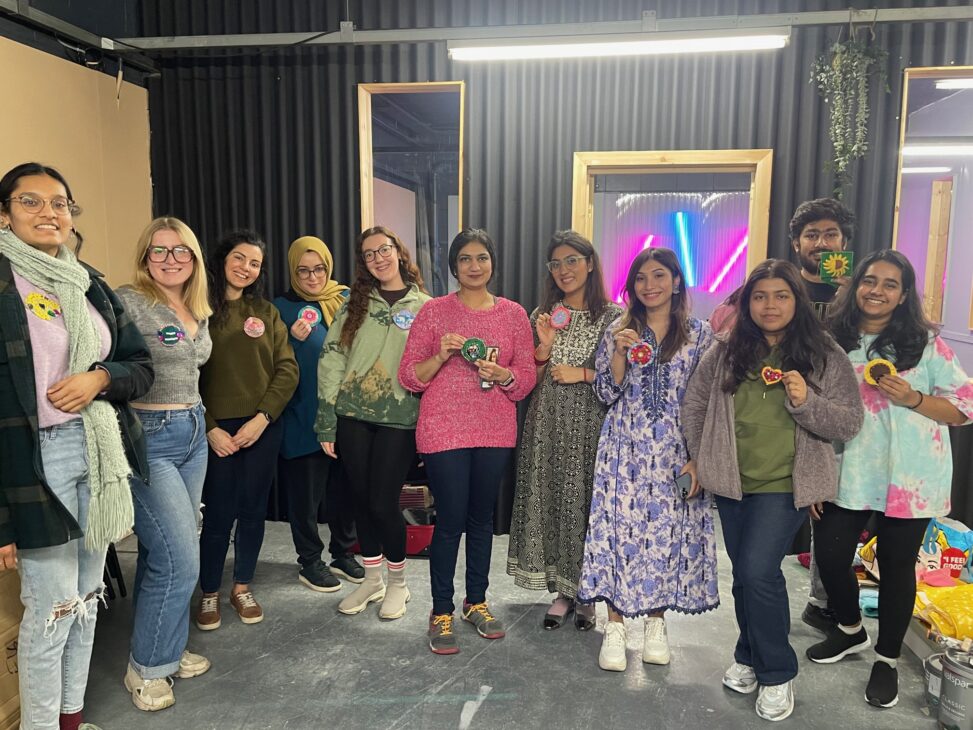 group of people holding up hand sewn brooches they have made